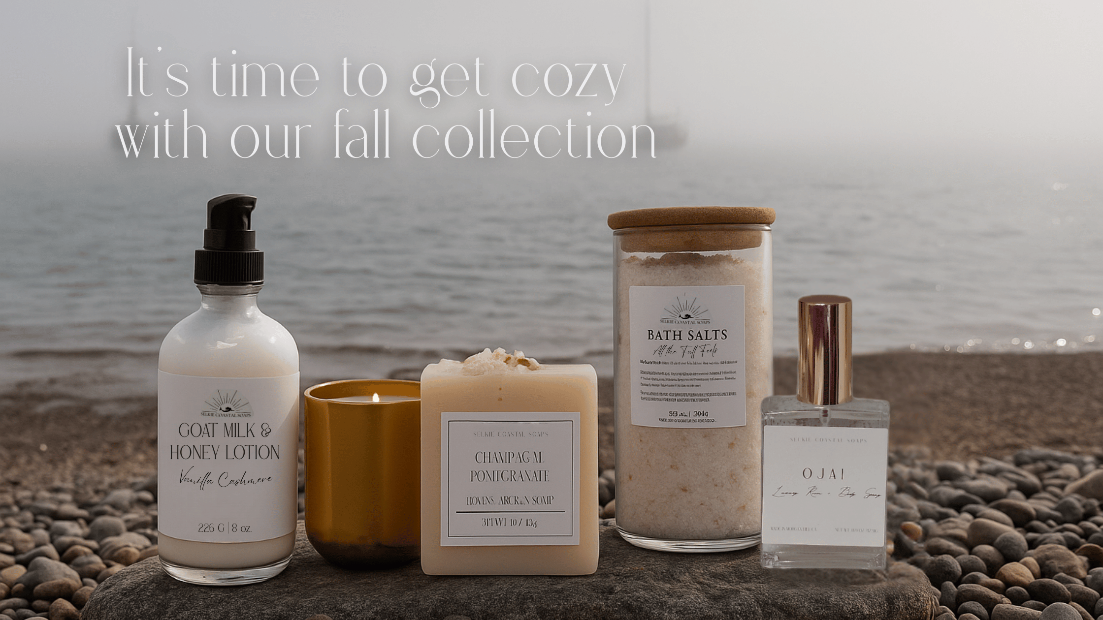 Bath products including lotion, candles, and bath salts on a stone surface with a beach background.